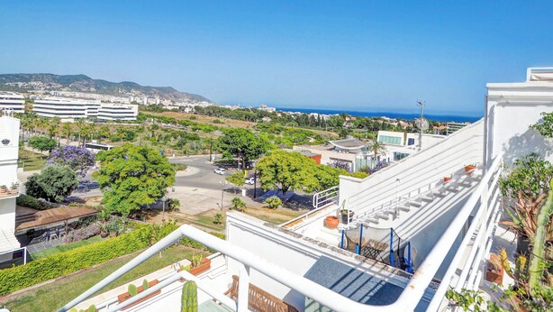 Un quartier résidentiel offrant une vue sur la mer, avec des bâtiments modernes et un ciel dégagé.