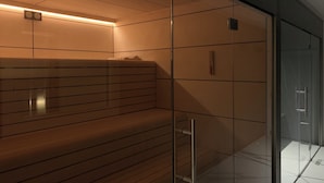 A modern sauna with a wooden bench, glass walls, and a ceiling with a light fixture. - Tropical Suite by Hello Homes Sitges (Sitges)