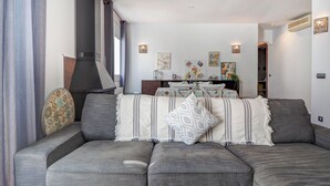 Una sala de estar moderna con un sofá seccional gris, una chimenea y un comedor con mesa y sillas.