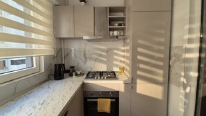Una cocina funcional con estufa a gas, horno y cafetera sobre la encimera.