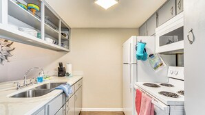 A compact kitchen with white cabinets, a double sink, a stove, and a refrigerator. - 4 Mi to Greers Ferry Lake: Condo w/ Deck & Balcony (Fairfield Bay)