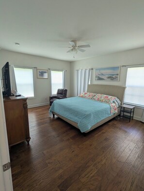 A bedroom with a bed, a chair, a desk, and a ceiling fan.