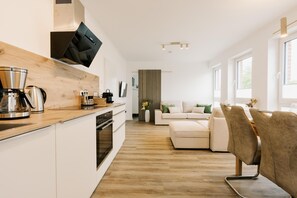 Une cuisine moderne dotée d’un plan de travail en bois, d’appareils électroménagers en acier inoxydable et d’un four encastré.