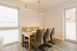 A dining area with a wooden table, four chairs, and a hanging light fixture.