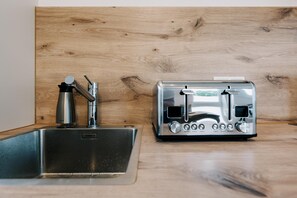 Un évier en acier inoxydable et un grille-pain sur un plan de travail en bois.