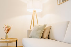 A room with a sofa, a lamp, a small table, and a vase with dried flowers. - Canals - Suite 1 | Direct Waterfront Location (Greetsiel)