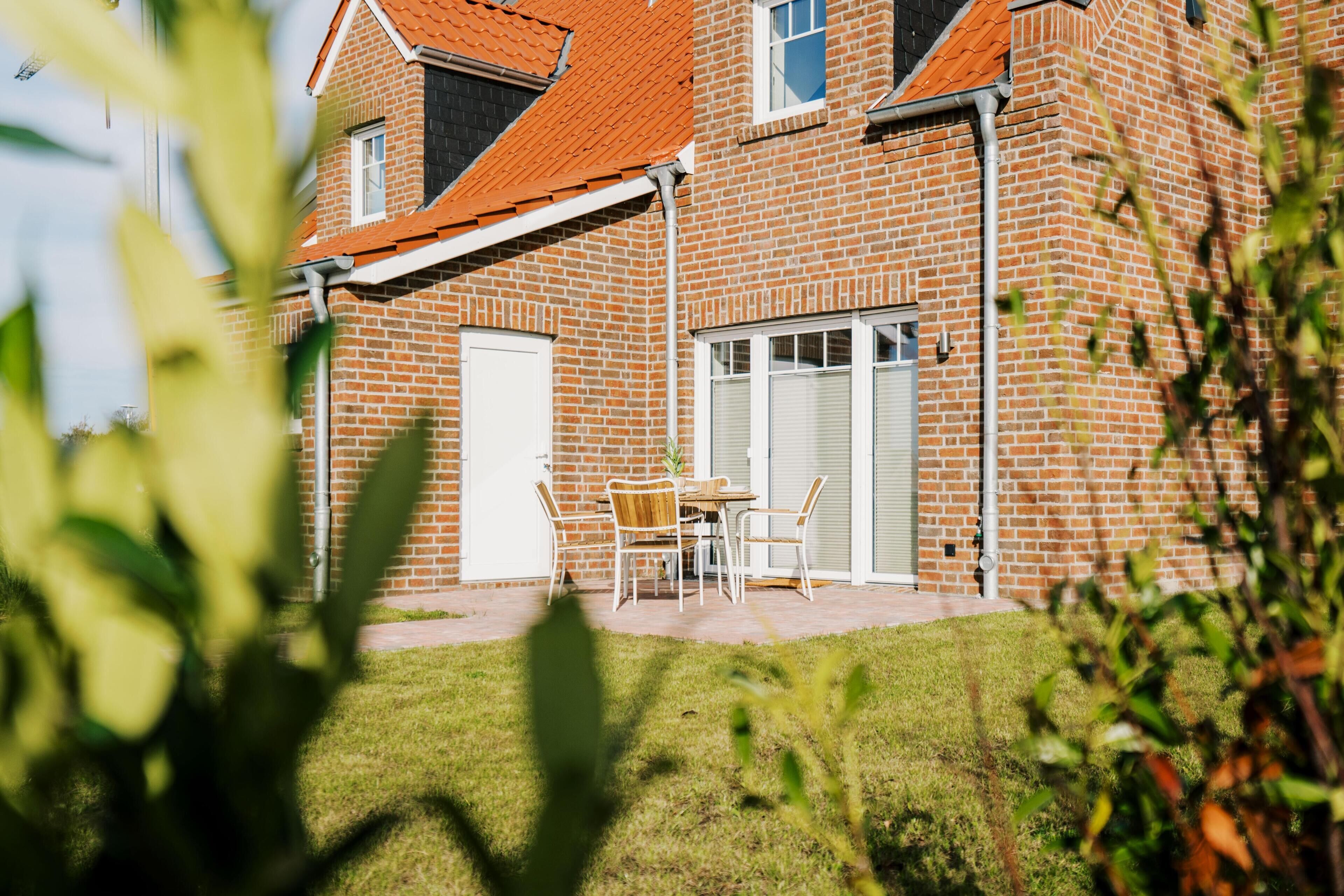Ein Ziegelhaus mit rotem Dach, einer überdachten Terrasse und einer weißen Tür.