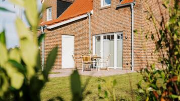 Ein Ziegelhaus mit rotem Dach, einer überdachten Terrasse und einer weißen Tür.