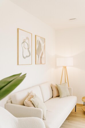 A modern living room with a sofa, a floor lamp, and abstract wall art. - Canals - Suite 2 | Direct Waterfront Location (Greetsiel)