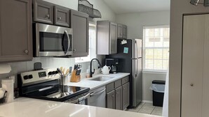 A modern kitchen with a central island, stainless steel appliances, and bar stools. - Charming 2-bedroom Penthouse condo with AC, WiFi in lovely BransonMo (Branson)
