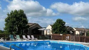 A rectangular swimming pool with a blue interior, surrounded by a wooden deck and a metal pool ladder. There are lounge chairs and umbrellas along the poolside. - Charming 2-bedroom Penthouse condo with AC, WiFi in lovely BransonMo (Branson)