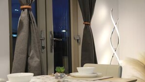 A dining area with a table set for two, a small plant, and a decorative light fixture.