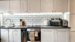 A modern kitchen with white cabinets, a stainless steel sink, and a built-in oven.