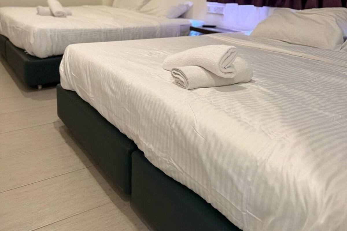 A hotel room with two beds, each with white linens and rolled towels.