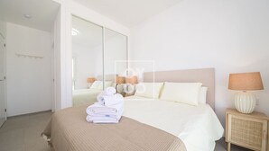 Une chambre d’hôtel avec un lit, une table de chevet avec une lampe et un grand miroir.