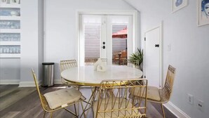 A dining area with a round table and six chairs, a trash can, and a door leading to another room. - 4 Bedroom - 4 Blocks to King St. with Parking (Charleston)