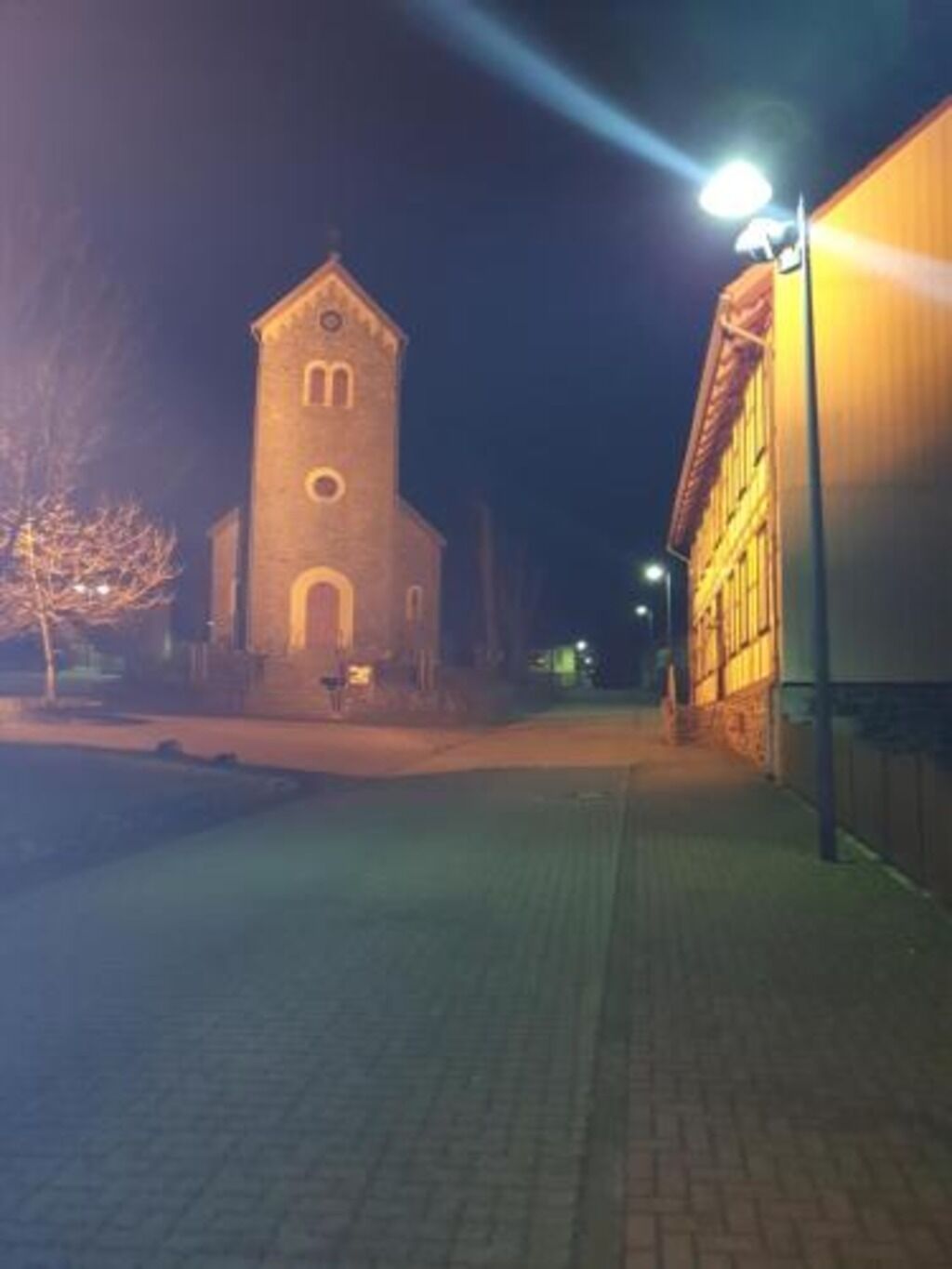 A brick building with a tower, a paved walkway, and a street lamp.
