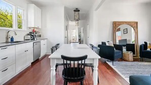 Una cocina amplia con armarios blancos, una isla central y un comedor con sillas.