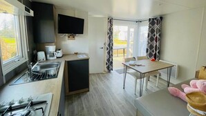 Une cuisine compacte équipée d’un évier, d’une cuisinière et d’un téléviseur à écran plat fixé au mur.