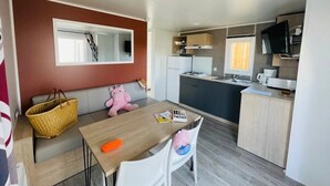 Un espace de vie compact comprenant un coin cuisine, un coin repas et un coin salon avec un canapé et un ours en peluche.