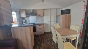 Une cuisine compacte comprenant un coin repas, des meubles de rangement en bois, un petit réfrigérateur et un téléviseur à écran plat.