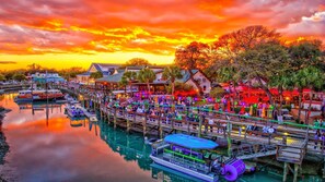 A waterfront area with docked boats, a pier with people, and buildings with signage.
