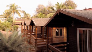 A wooden bungalow with a balcony, surrounded by palm trees. - Surf House Beach Resort (Baga)