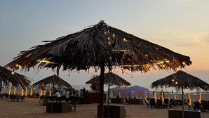 A beach with thatched umbrellas and seating areas. - Surf House Beach Resort (Baga)