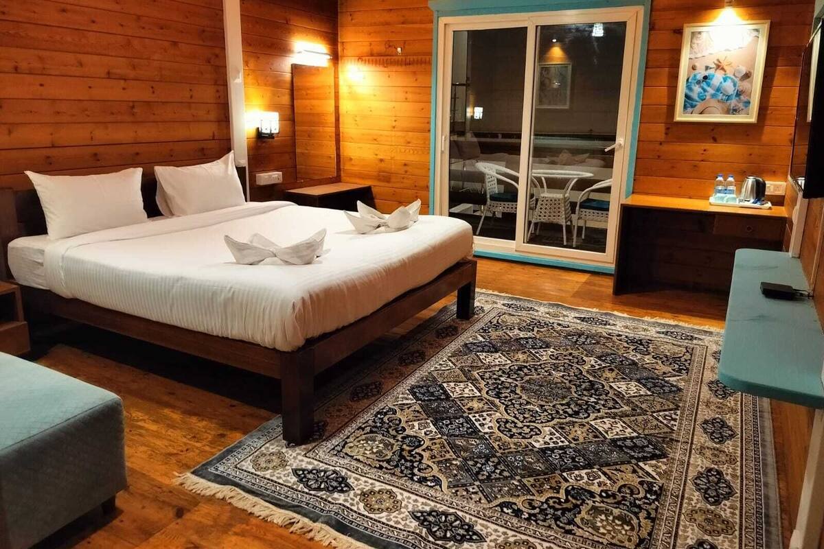 A wooden cabin bedroom with a bed, a small table, and a chair.