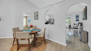 Una cocina moderna con armarios blancos, un refrigerador de acero inoxidable y un comedor con una mesa redonda y sillas.