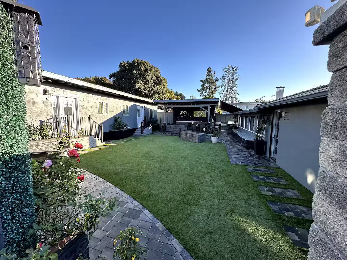 Een modern woonhuis met een verzorgd gazon, een patio en een stenen muur.