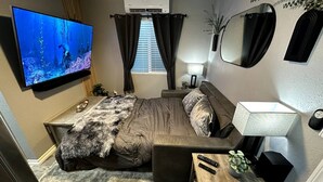 A bedroom with a bed, a TV, a desk, and a mirror. - Welcome to SD Cozy Home - B (La Mesa)