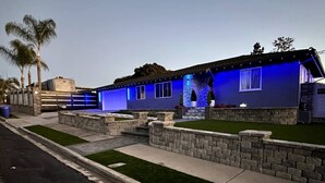 A house with a garage, a well-maintained lawn, and a stone retaining wall. - Welcome to SD Cozy Home - B (La Mesa)