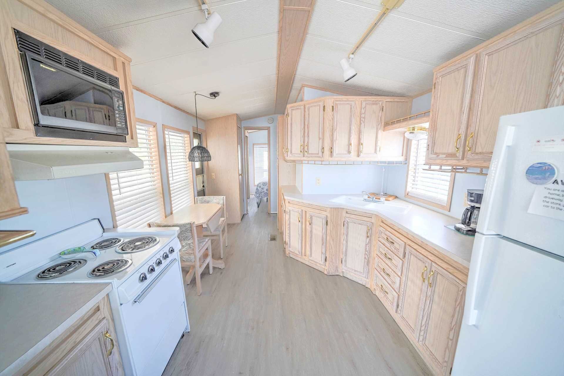 A compact kitchen with wooden cabinets, a white stove, and a refrigerator.
