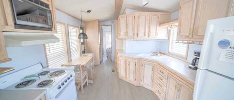 A compact kitchen with wooden cabinets, a white stove, and a refrigerator.