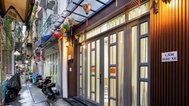 A narrow alley with parked motorcycles, a wooden building with large windows, and a sign reading "CÂM ĐÀU XE". - Luxhome (Ho Chi Minh City)