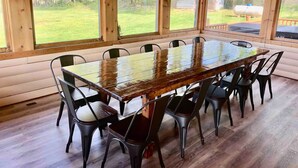 A wooden dining area with a large table and chairs, large windows, and a view of the outdoors.