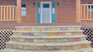 A wooden building with a blue door, stone steps, and a wooden railing.