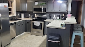Una cocina moderna con electrodomésticos de acero inoxidable, encimeras de granito y armarios grises.