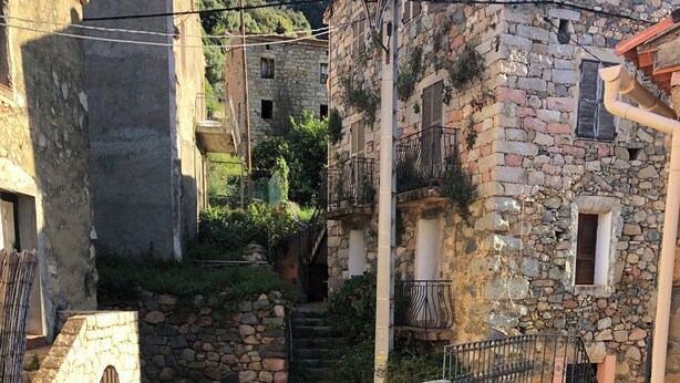 A stone staircase leading to a traditional stone building with a wooden door and metal railings.