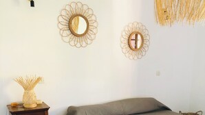A bedroom with a bed, a small wooden nightstand, a woven floor mat, and two wall-mounted mirrors.