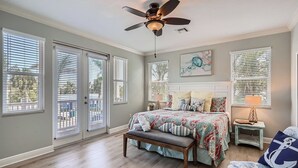 A bedroom with a bed, bench, ceiling fan, and artwork. - Location! Family Friendly, Pool, Elevator, Close to Beach (Holmes Beach)