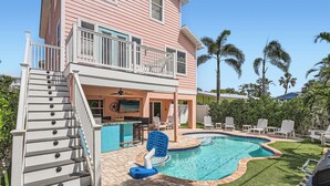 A two-story house with a backyard swimming pool, a barbecue area, and a patio with lounge chairs. - Location! Family Friendly, Pool, Elevator, Close to Beach (Holmes Beach)