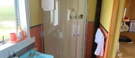 A bathroom with a shower, sink, and window.