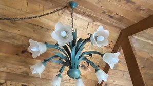 Een houten plafond met een kroonluchter, versierd met meerdere witte bloemen en een turquoise element.