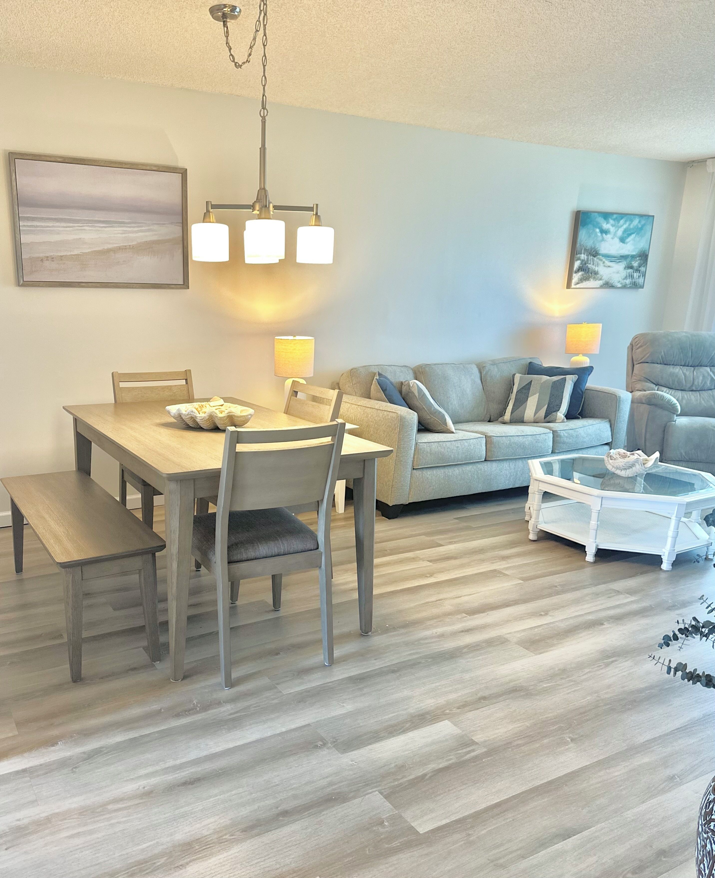 A modern living room with a dining table, sofa, and armchair.