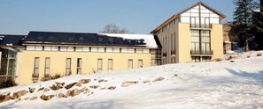Ein modernes Gebäude mit flachem Dach und großen Fenstern, umgeben von Schnee.