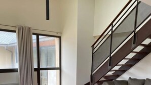 A modern living room with a dining table, two chairs, a coffee table, a sofa, and a staircase. - ZEcamping 3* locatif TV clim 41m2 4 pers (Saint-Lizier)