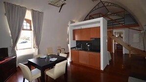 A dining area with a table and chairs, a kitchen with wooden cabinets, and a staircase leading to an upper level. - ZEcamping 3 étoiles pet friendly locatif TV clim 48m2 6 pers (Saint-Lizier)