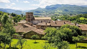 A historic building with a prominent tower, surrounded by lush greenery and a mountainous backdrop. - ZEcamping 3 étoiles pet friendly locatif TV clim 48m2 6 pers (Saint-Lizier)